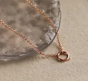 Detailed close-up of rose gold geometric circle necklace on elegant stone background