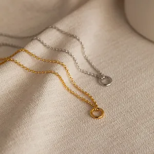 Minimalist geometric circular pendant necklaces in gold and silver on soft fabric