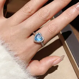 Macro detail of 18k silver plated heart ring with sea blue stone and halo diamonds