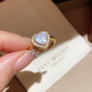 Detailed view of 18k gold plated heart ring with sparkling zirconia held by hand
