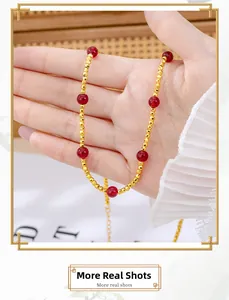 Detailed shot of gold beaded necklace with red gemstones and adjustable link chain