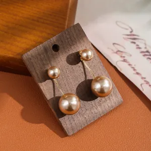 Detail of elegant two-way pearl earrings with gold chains on a dark wooden display