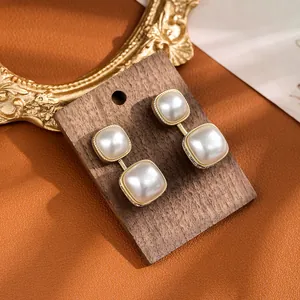 Detailed macro view of square pearl earrings with gold plating on a wooden display