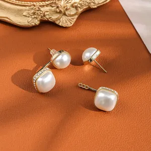 Detailed macro of gold square pearl earrings with diamond accents on leather background