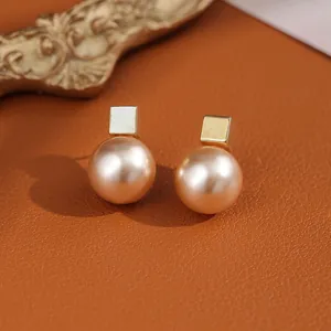 Macro shot of golden square studs with champagne pearls on brown leather base