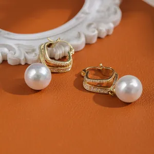 Macro detail of gold-plated pearl drop earrings with sparkling pavé crystal square studs