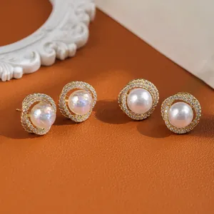 Elegant gold-plated pearl stud earrings with sparkling crystal halo on leather background