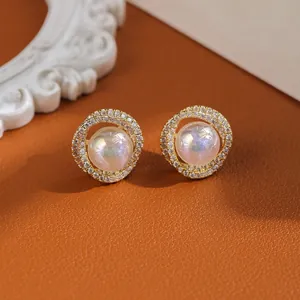 Detail of gold pearl earrings with shimmering cubic zirconia pavé and iridescent center