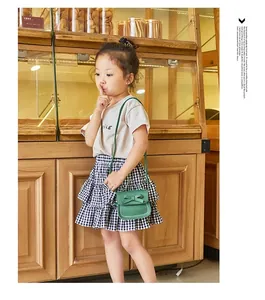 Green kids bow shoulder bag with white stitching detail worn by a little girl
