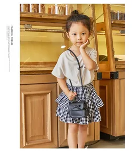 Detail of a black mini bow shoulder bag worn by a girl in a cozy cafe setting