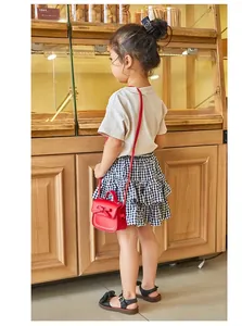 Detailed view of red mini bow crossbody bag for girls styled on a child model