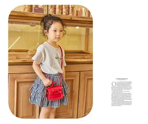 Close-up of a red mini girls' shoulder bag with a bow and white stitching detail