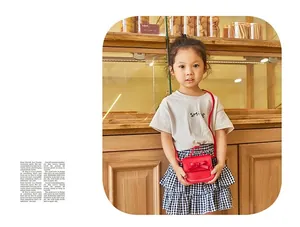 Detailed view of a red mini crossbody bag with bow decoration worn by a child in a cafe