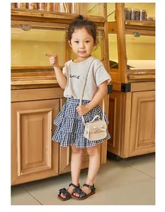 Detail of girls grey SMILE t-shirt and blue checkered tiered skirt summer outfit