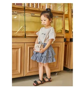 Close-up of girl wearing mini bow crossbody bag with smile t-shirt and plaid skirt