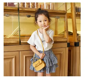 Detail of a mini yellow bow crossbody bag paired with a smile T-shirt and plaid skirt