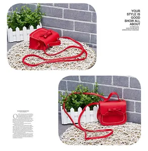 Detail view of red PU leather girls crossbody bag with white stitching and bow accent