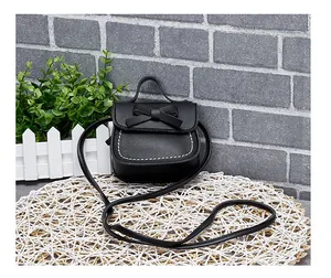 Detail of girls mini crossbody bag featuring a black bow and contrast white stitching