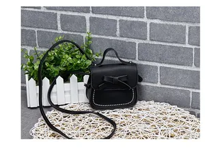 Detail of a mini black crossbody bag for girls featuring a bow and white stitching