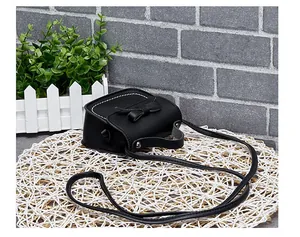 Detail of black mini crossbody bag featuring white contrast stitching and a bow accent