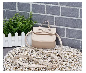 Detail of a beige mini bow purse for girls with stitching on a round straw mat