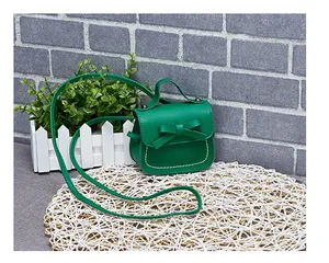 Detail view of mini green girls' shoulder bag with bow knot and white stitching