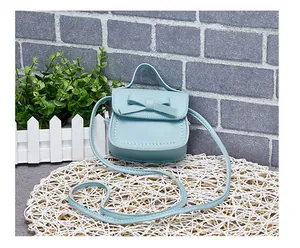 Detail of light blue mini bag with bow decoration and white stitching on PU leather