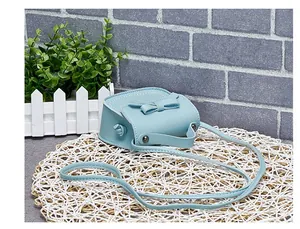 Detail view of light blue mini girls bag with bow decoration on white woven mat