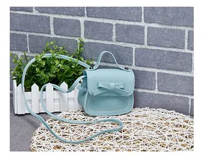 Detail of light blue mini bag featuring bow decoration and fine white stitching details