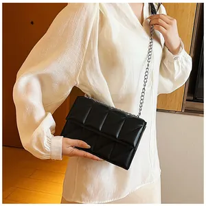 Detail of black quilted crossbody bag with silver chain strap and 3D geometric texture