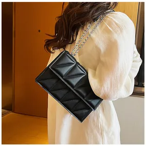 Side view of woman wearing a black quilted crossbody bag with silver chain strap