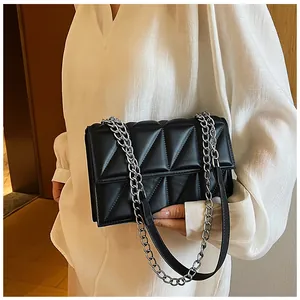 Close-up of black quilted triangular leather bag with silver metal chain strap detail