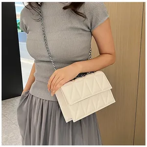 Quilted crossbody bag in beige worn by a model with a silver chain shoulder strap
