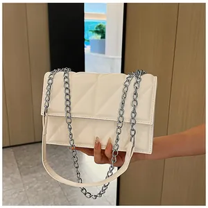 Close-up of off-white quilted crossbody bag featuring polished silver chain and glossy finish