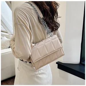 Detail of light beige quilted crossbody bag with silver chain strap and geometric pattern