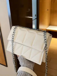 White quilted crossbody bag with silver chain strap shown in a modern minimalist setting