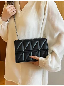 Minimalist black quilted crossbody bag with silver chain strap shown on model shoulder