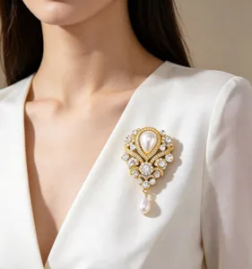 Detail einer Barock-Brosche mit weißen Perlen und Kristallen an einem weißen Blazer