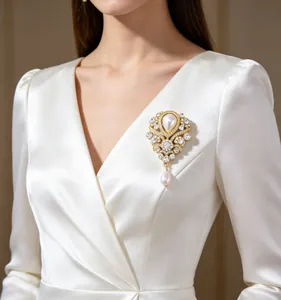 Nahaufnahme einer Vintage-Perlenbrosche mit Tropfenanhänger an weißem Kleid