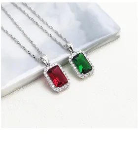 Detail of emerald and ruby rectangular pendants with halo diamonds on silver chains