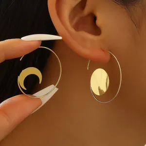 Gold hoop earrings featuring crescent moon and solid disc pendants on model