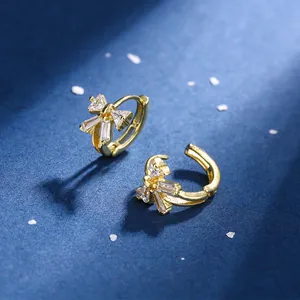 Elegant gold bow earrings with crystal zircon stones on a navy blue background