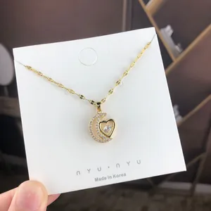 Gold moon and heart pendant necklace with sparkling crystals on a white display card