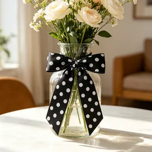 Detail of a black and white polka dot satin bow tied on a glass vase for home decor