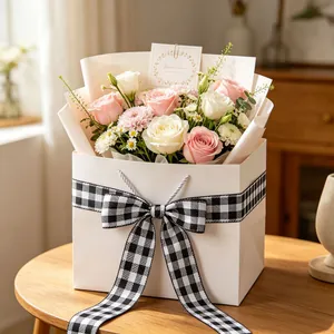 Close-up of pink rose bouquet in white gift bag with black checkered bow and card