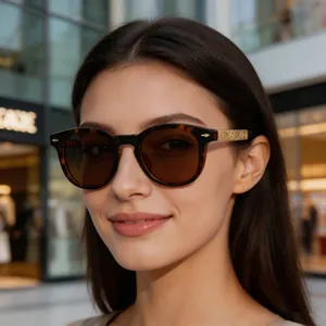 Detail of square tortoiseshell sunglasses with engraved gold metal temples on female model