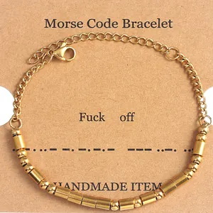 Detail view of gold Morse code beads spelling Fuck Off on a brown kraft card display