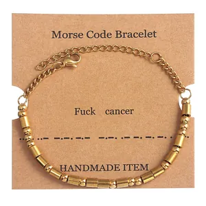 Gold Morse Code bracelet with beads and cylindrical bars on kraft paper card display