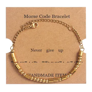 Close-up of golden Morse Code beads on card with Never Give Up inspirational quote
