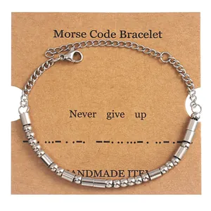 Detail of silver Morse Code bracelet on Kraft paper card with Never Give Up message